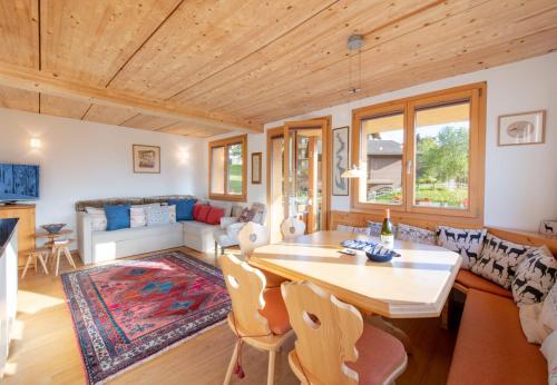 a living room with a wooden ceiling and a table and chairs at Chalet Stella Duplex Penthouse in Wengen