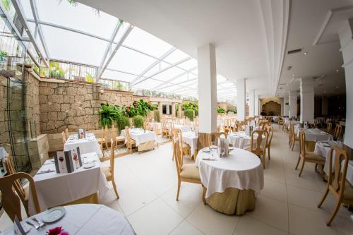 un restaurant avec des tables et des chaises blanches et un plafond en verre dans l'établissement Apartamentos Parque del Sol, à Adeje