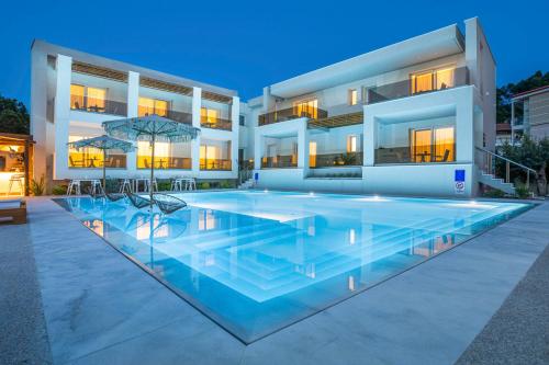 a house with a large swimming pool in front of it at Mirablue Luxury Residences in Pefkochori