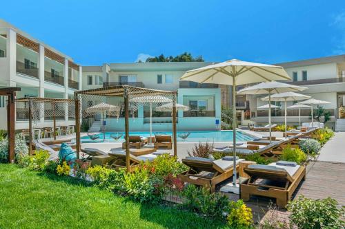 - une piscine avec des chaises longues et des parasols dans l'établissement Mirablue Luxury Residences, à Pefkohori