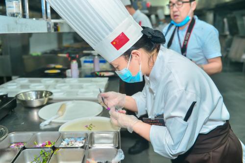 a woman in a chefs outfit preparing food in a kitchen at Wyndham Chongqing Yuelai in Chongqing