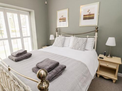 a bedroom with a white bed with towels on it at Kizzie Cottage in Morpeth