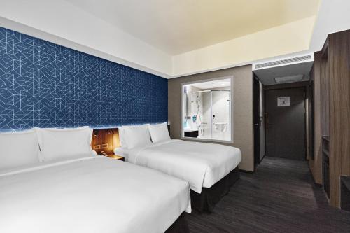 a hotel room with two beds and a blue wall at Holiday Inn Express Kaohsiung Love River by IHG in Kaohsiung