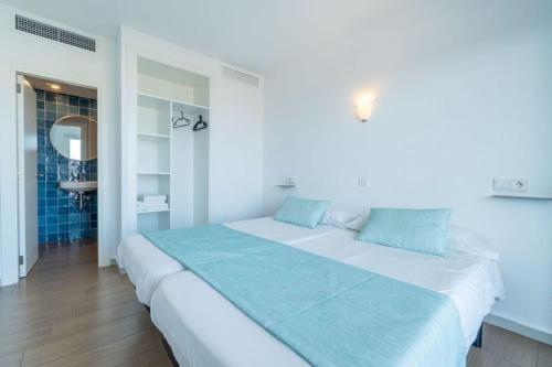 a bedroom with a large white bed with blue pillows at Apartaments La Perla Negra in Cala Ratjada