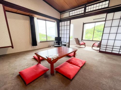 大島にある癒楽 伊豆大島のリビングルーム(テーブル、赤い椅子2脚付)