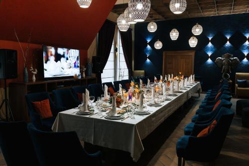 a dining room with a long table and blue chairs at Medeu in Kostanay