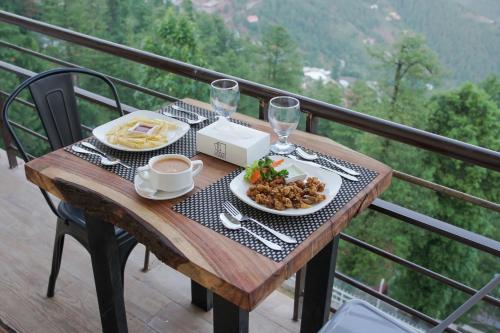 a table with a plate of food on a balcony at The Roomy Lodge, Murree in Murree