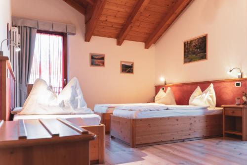 a hotel room with two beds and a desk at Agritur Bella di Bosco in Coredo