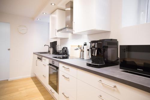 a kitchen with white cabinets and a black counter top at Ferienwohnung Am Kahlenberg - Ringsheim in Ringsheim