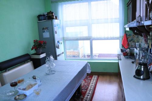 a kitchen with a table and a refrigerator and a window at Guest House Oimo in Balykchy