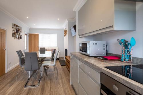 a kitchen with a counter top with a table and chairs at Pigwig Cottage, Thorpeness in Thorpeness