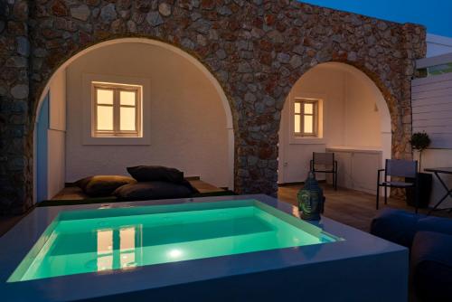 a swimming pool in a living room with a stone wall at Kasteli Suites in Perivolos