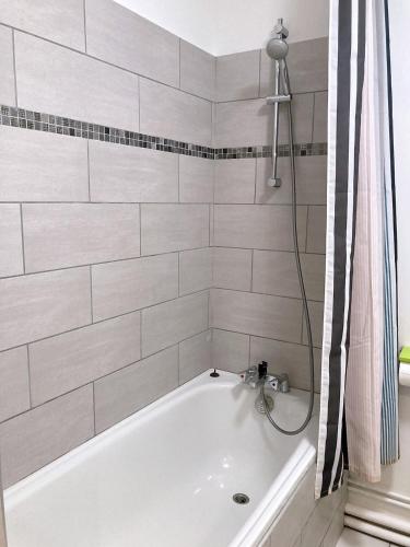 La salle de bains est pourvue d'une baignoire blanche et de carrelage blanc. dans l'établissement Chez Karine 1, à Arpajon