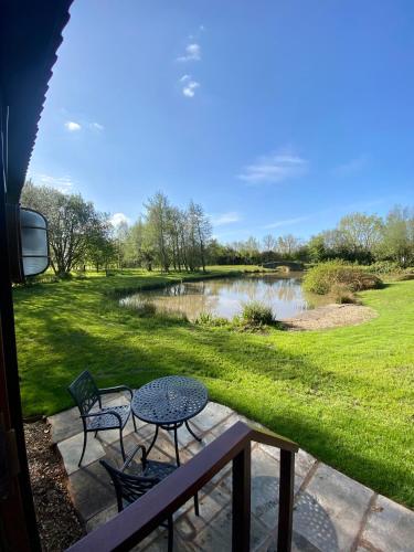 a patio with a table and chairs next to a pond at Heywood Glamping in Ormskirk