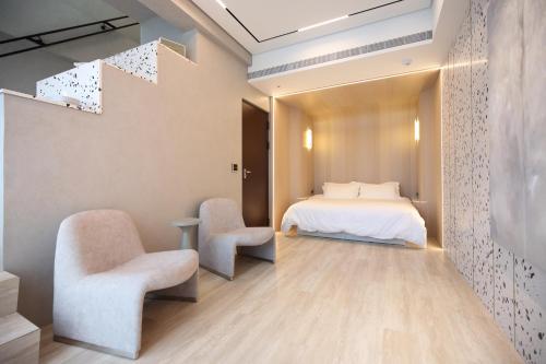 1 dormitorio con 1 cama y 2 sillas en Fleur Villa en Hualien