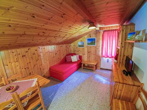 a living room with a red couch in a wooden room at La Piana Appartamenti in Alpe Devero