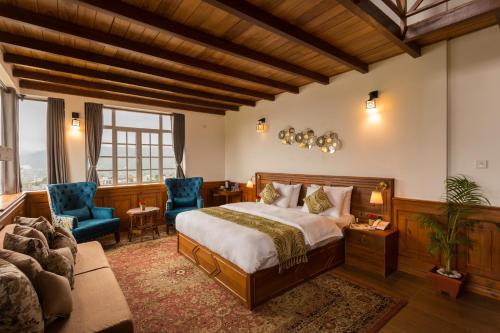 a bedroom with a bed and two blue chairs at C I Residence in Nuwara Eliya