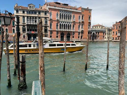 a yellow boat in the water in front of buildings at Familly rooms (two rooms) Cà del Traghetto in Venice