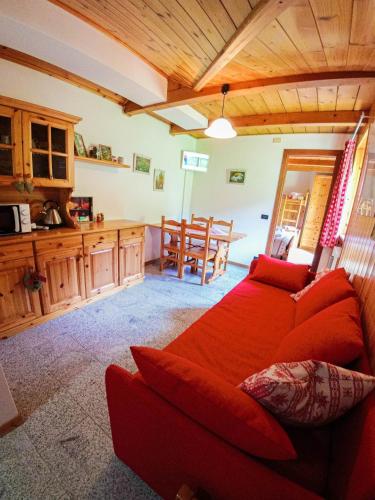 a living room with a red couch and a kitchen at La Piana Appartamenti in Alpe Devero
