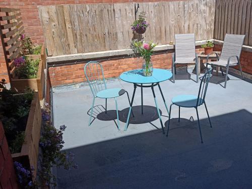 a patio with chairs and a table with a vase of flowers at Bluebell Apartment in Swanage