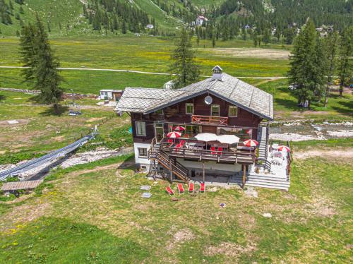 a house with tables and umbrellas in front of it at La Piana Appartamenti in Alpe Devero