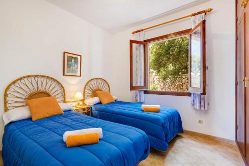 two blue beds in a room with a window at Villa Casa Blanca by Villa Plus in Cala Blanca