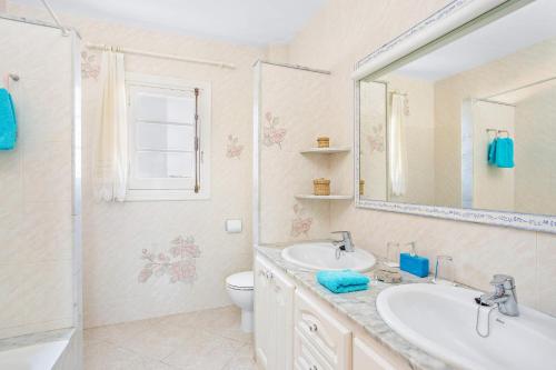 łazienka z umywalką, toaletą i lustrem w obiekcie Villa Sunflower by Villa Plus w mieście Cala Blanca