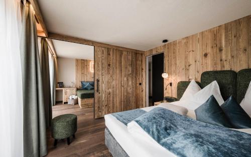 - une chambre avec un lit et des murs en bois dans l'établissement Hotel Goldknopf, à Alpe di Siusi