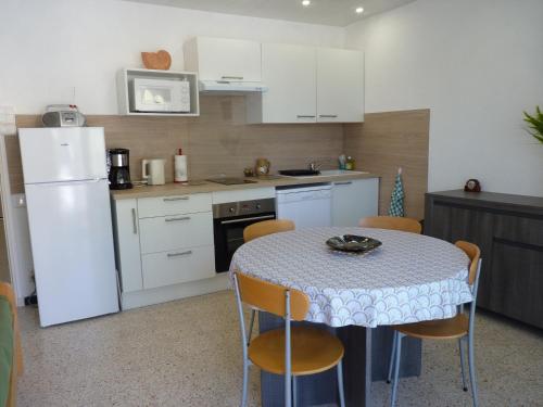 Il comprend une cuisine équipée d'une table avec des chaises et d'un réfrigérateur blanc. dans l'établissement Sol-y-Days Hespérides, Appartement familial 5 couchages, quartier calme à 50m de la plage, au Grau-du-Roi