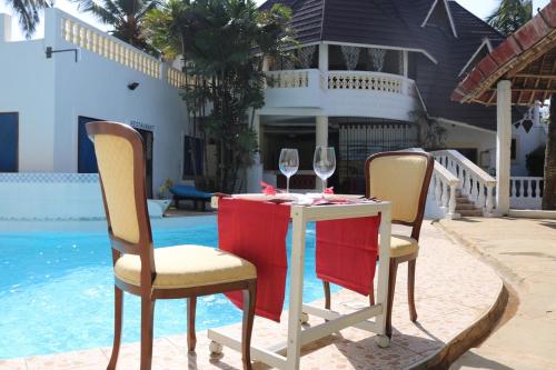 a table with two glasses of wine next to a pool at 4 Bed Villa - Sleeps 8 - Wifi - Pool - Garden in Diani Beach