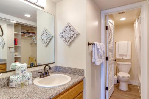 a bathroom with a sink and a toilet and a mirror at K B M Resorts- VIR-1204 Penthouse Ocean Views! in Kahana
