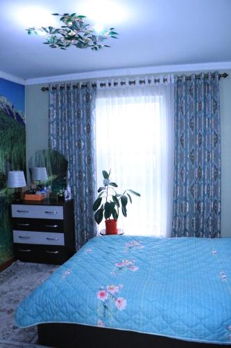 a bedroom with a blue bed and a window at Guest House Oimo in Balykchy