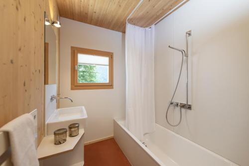 a bathroom with a tub and a sink and a shower at Chasa Laina in Sent