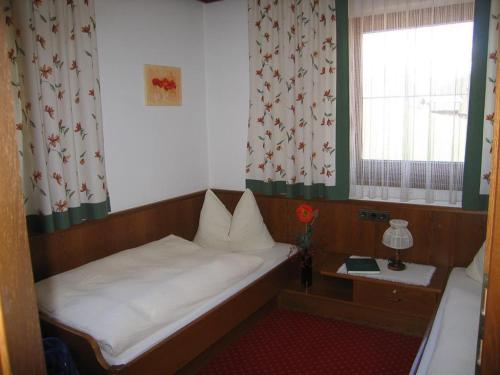 małe łóżko w małym pokoju z oknem w obiekcie Jakob, Landhaus w mieście Tux