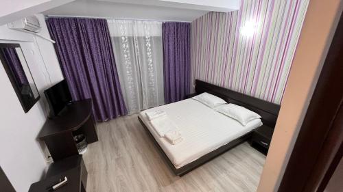 a small bedroom with a bed and purple curtains at Vila Sunrise Costinesti in Costinesti