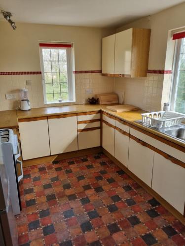 a kitchen with white cabinets and a tile floor at Lovely 2-Bedroom New Forest apartment on a Farm in New Milton