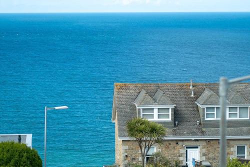 a house with the ocean in the background at Wingtips in Carbis Bay