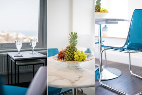 a bowl of fruit on a table and a blue chair at Harbour Vista in St Ives