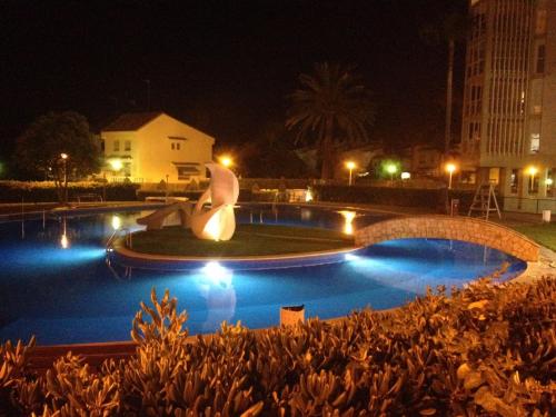 una piscina por la noche con una estatua en el medio en MAGNIFICO ATICO-DUPLEX FRENTE AL MAR, en El Puig