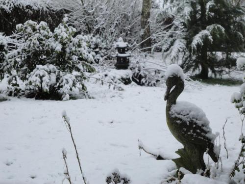 a bird statue in a garden covered in snow at Relax à Maison Sax Kingsize in Durbuy