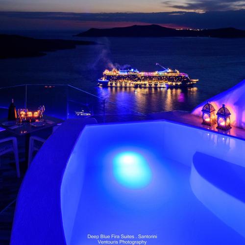 a cruise ship in the water at night at Fira Deep Blue Suites in Fira