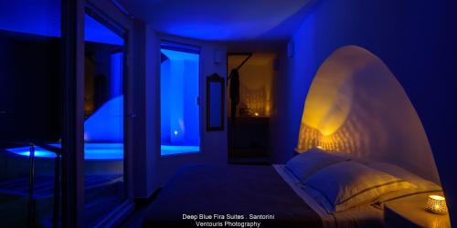 a bed in a room with a blue light at Fira Deep Blue Suites in Fira
