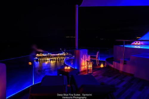 a night view of a pool with a boat in the water at Fira Deep Blue Suites in Fira