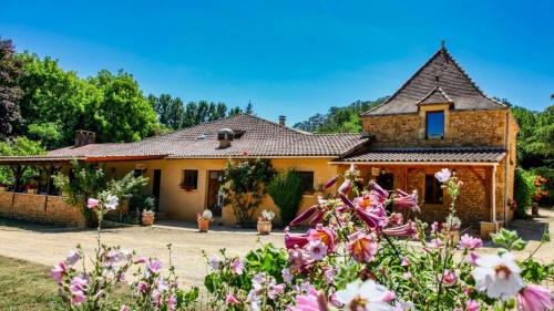 une maison avec des fleurs devant dans l'établissement Ferme Auberge Du Roc, à Les Vauries