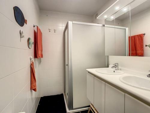 a white bathroom with a sink and a shower at Comfortabel Gezinsappartement 'Emmy' te Oostduinkerke in Oostduinkerke