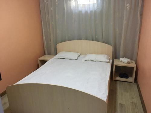 un letto con lenzuola e cuscini bianchi in una camera da letto di Гостиница"Hostel" a Karagandy