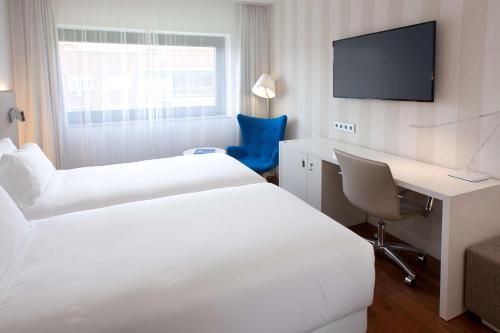 a hotel room with two beds and a desk and a tv at NH Madrid Ventas in Madrid