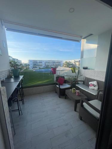 a balcony with couches and chairs and a table at Superbe appartement en résidence avec piscine in Sidi Rahal