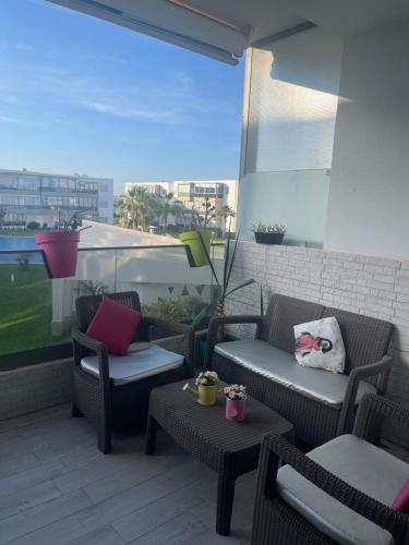 a patio with chairs and tables on a balcony at Superbe appartement en résidence avec piscine in Sidi Rahal