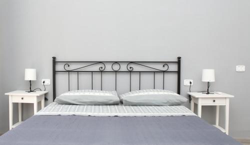 a bed with two white tables and two pillows at Suite Garibaldi in Cefalù